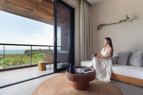 a woman standing in a living room with a table at 1 Hotel Haitang Bay, Sanya in Sanya