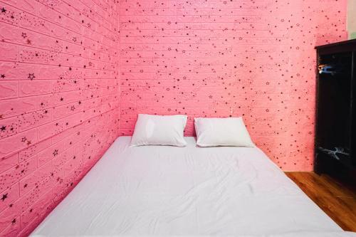 a bed in a pink room with a brick wall at Penginapan Dison RedPartner in Bekasi
