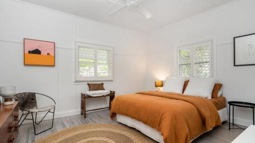 a bedroom with a bed and a desk and two windows at Brunswick Beach Shack in Brunswick Heads
