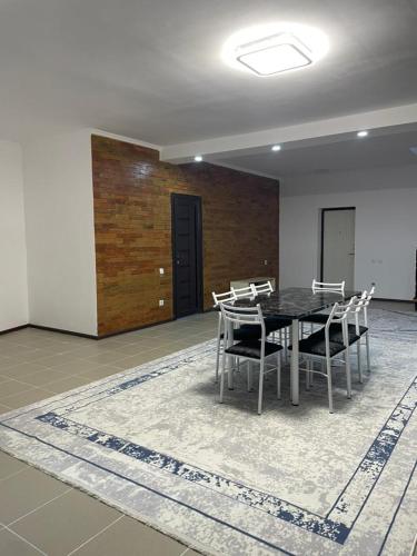 a dining room with a table and chairs on a rug at Laguna City Lux in Tegirmenty