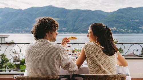 a man and a woman sitting at a table eating food at Boutique Hotel Sunstar Brissago am Lago Maggiore in Brissago