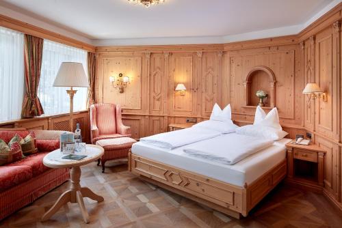 a bedroom with a large bed and a red couch at Hotel Neue Post in Mayrhofen