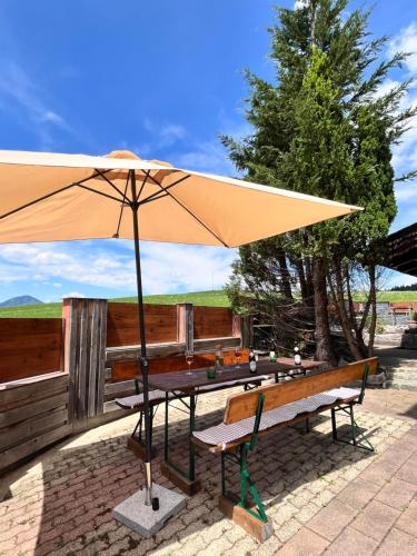 a picnic table with an umbrella and a bench at Ferienhaus Praschberg in Niederndorferberg