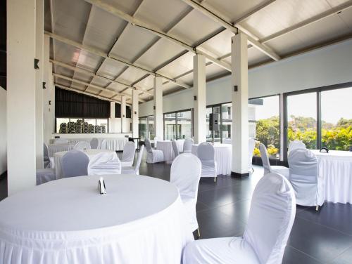 a room with white tables and chairs and windows at Crystal Village in Nagoa-Bardez