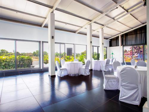 a room with white chairs and tables and windows at Crystal Village in Nagoa-Bardez