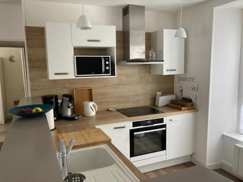 une cuisine avec des armoires blanches et un comptoir dans l'établissement Les Chamois du Sancy, à Le Mont-Dore