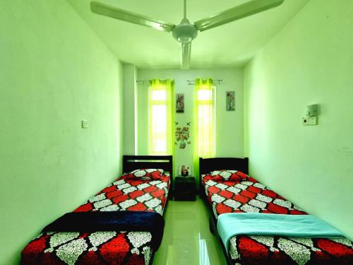 two beds sitting in a room with green floors at Dane & Shue Hotel Kok Lanas in Kota Bharu