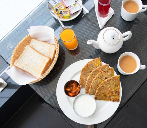 a table with a plate of bread and eggs and coffee at Crystal Village in Nagoa-Bardez