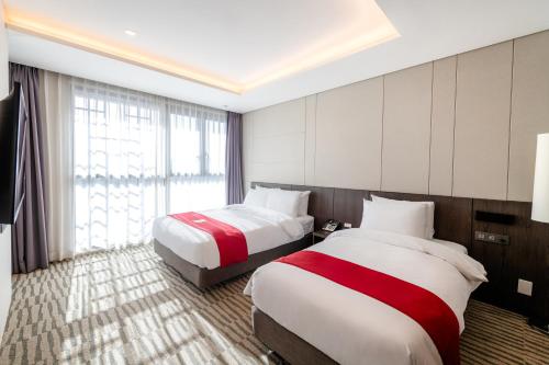 a hotel room with two beds and a window at Best Western Plus Jeonju in Jeonju
