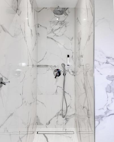 a bathroom with a shower with white marble walls at Almira Hotel in Troulos