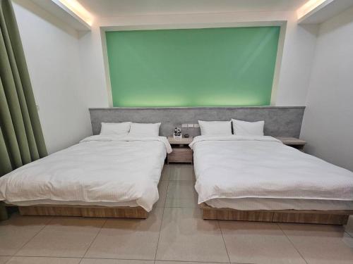 two beds in a room with a projection screen at Hongyue Holiday B&B in Toucheng