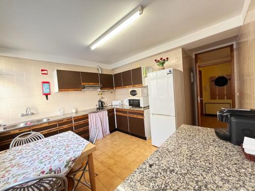 a kitchen with a white refrigerator and a table at Two bedroom apartment near beach and Casino in Figueira da Foz