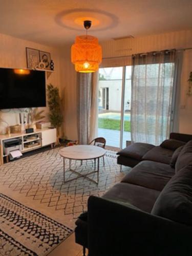 un salon avec un canapé et une table dans l'établissement Maison familial piscine près de bordeaux 2 chambres, à Artigues-près-Bordeaux