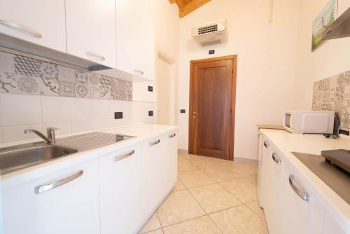 a white kitchen with a sink and a microwave at Agriturismo Bortolino in Volta Mantovana