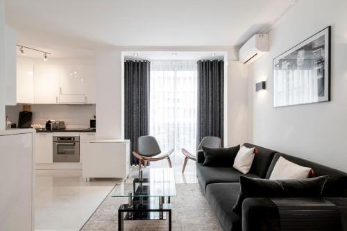 un salon avec un canapé noir et une cuisine dans l'établissement REF 1380 - Cannes Croisette - Apartment for rent, à Cannes