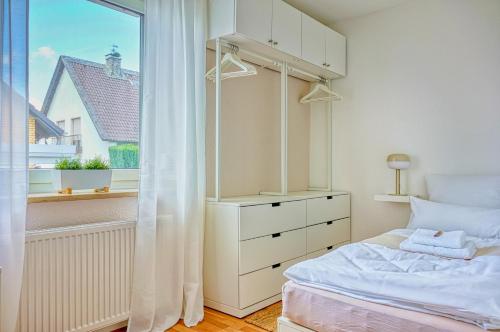 a white bedroom with a bed and a window at Modern & gepflegt, Süd-Terrasse, Parkplatz, Nähe DUS in Kaarst