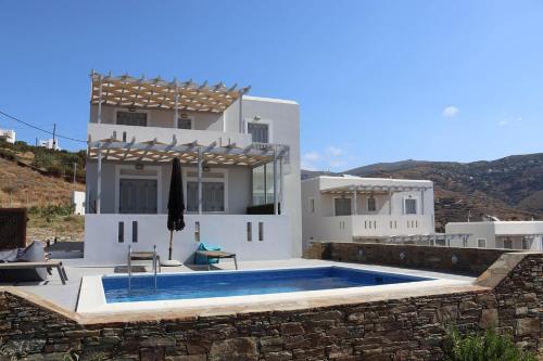 a villa with a swimming pool in front of a house at Antigoni Villas in Gavrio