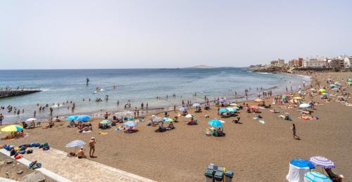 a crowd of people on a beach with umbrellas at El Reino Azul de Gran Canaria in Melenara