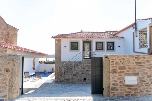 a house with white walls and a stone wall at Guest House Taião in Valença