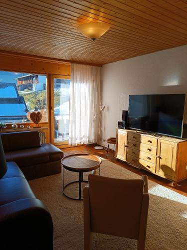 a living room with a tv and a couch and a table at Haus Obermaiselstein in Obermaiselstein