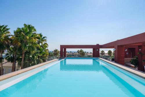 a swimming pool in a resort with palm trees at Apartamentos Estival Park in La Pineda