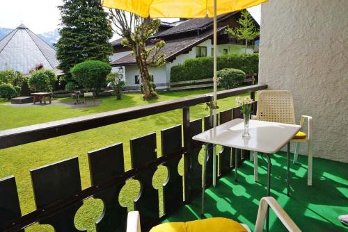 a table and chairs on a balcony with a garden at Haus Obermaiselstein in Obermaiselstein