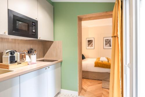 - une cuisine équipée d'un four micro-ondes et un lit dans une chambre dans l'établissement Charming Studio with terrace - Near Montmartre, à Paris