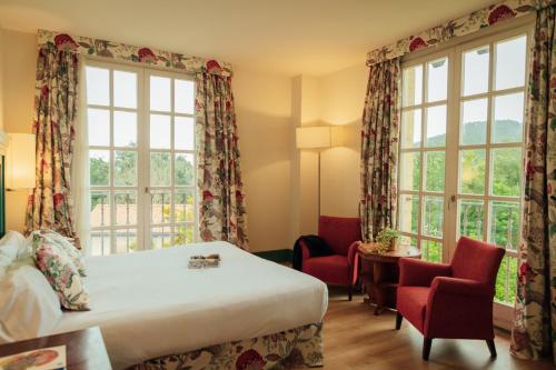 a hotel room with a bed and chairs and windows at Hotel Palacio Urgoiti in Mungia