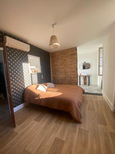 une chambre avec un grand lit avec un plancher en bois dans l'établissement Jolie maison traditionnelle, à Allassac