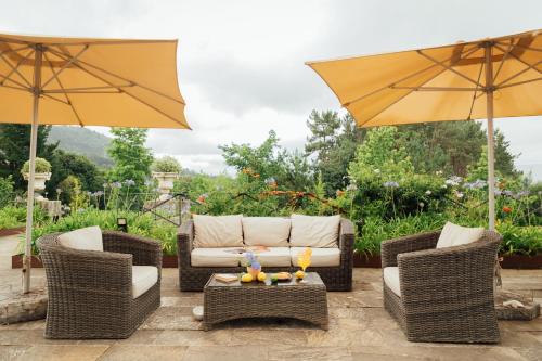 a patio with two wicker chairs and an umbrella at Hotel Palacio Urgoiti in Mungia