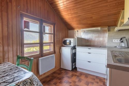 Il comprend une cuisine équipée d'un réfrigérateur, d'un évier et d'une fenêtre. dans l'établissement Les Serinthes - Pour 4 station accessible à pied, à Saint-Léger-les-Mélèzes