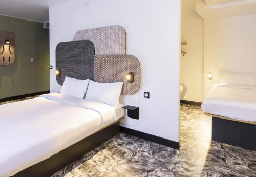 a hotel room with two beds and a headboard at B&B HOTEL Toulouse Cité de l'Espace Gonord in Toulouse