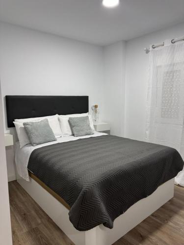 a white bedroom with a large bed with black comforter at Linerlife in Málaga