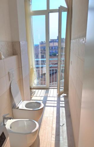 a bathroom with a toilet and a large window at Attico Saluzzo centro in Saluzzo