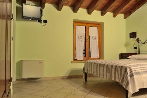 a bedroom with a bed and a television on the wall at Agriturismo Bortolino in Volta Mantovana