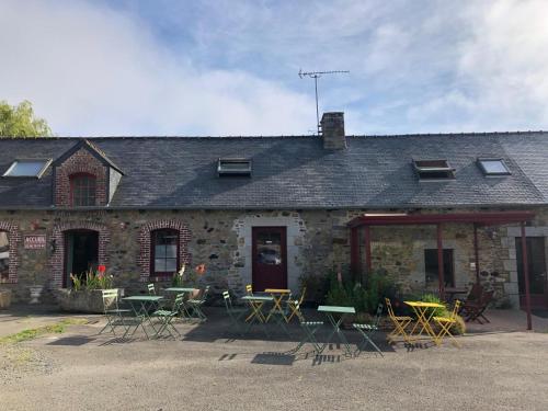 a building with tables and chairs in front of it at Hôtel Les Voisins Beaucemaine in Ploufragan