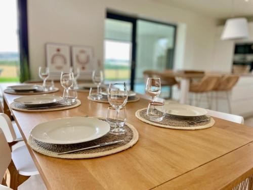 une table en bois avec des assiettes et des verres à vin dessus dans l'établissement Magnifique maison vue mer avec piscine intérieure, à Carantec