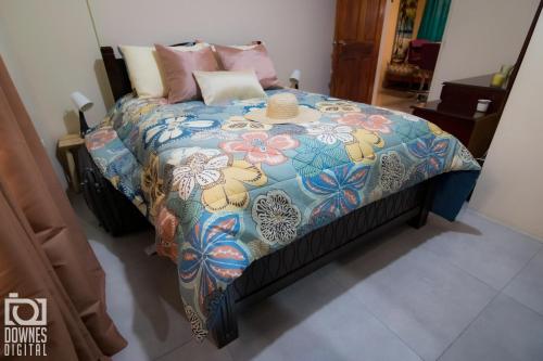 a bed with a colorful comforter with a hat on it at Casa Cicada at 18 Cicada Drive in Jerningham Junction