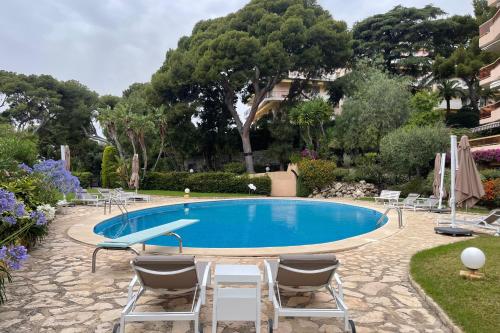 una grande piscina con sedie e alberi di Studio Azur - Happy Rentals a Cap d'Ail