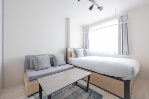 a bedroom with a bed and a couch and a window at K-room in Tokyo