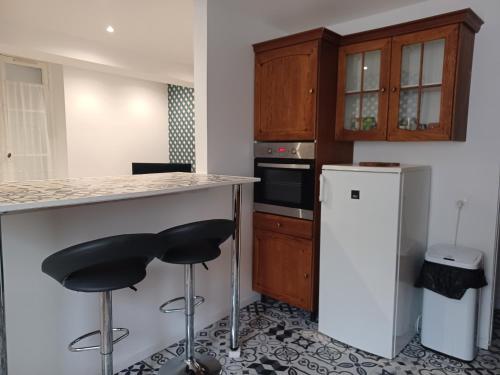 une cuisine avec deux tabourets de bar et un comptoir dans l'établissement Maison au pied du château, à Châteaudun