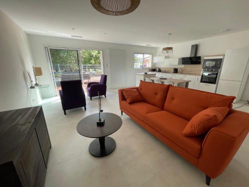 un salon avec un canapé orange et une table dans l'établissement Clos des Amandiers, à Balaruc-les-Bains