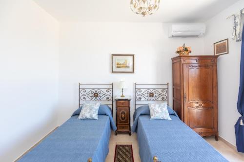 Dos camas en un dormitorio con sábanas azules. en Casale Antiche Mura Siracusa, en Siracusa