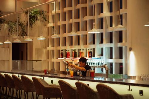 a man sitting at a bar in a restaurant at Wink Hotel Tuy Hoa Beach - 24hrs Stay & Rooftop Pool Bar in Tuy Hoa