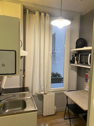 une petite cuisine avec un évier et une fenêtre dans l'établissement Studio central, à Paris