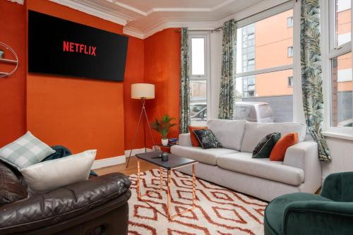 a living room with two couches and an orange wall at Stunning 5 bedroom home Wirral Birkenhead Sleeps 9- Free Parking-5G Internet in Birkenhead