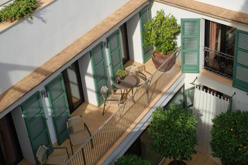 an apartment balcony with green shutters and a table and chairs at Can Alomar Hotel in Palma de Mallorca
