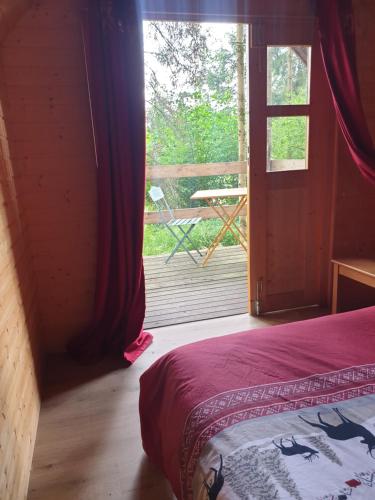 - une chambre avec un lit et une fenêtre avec une terrasse dans l'établissement White wood lodge, à Nonville