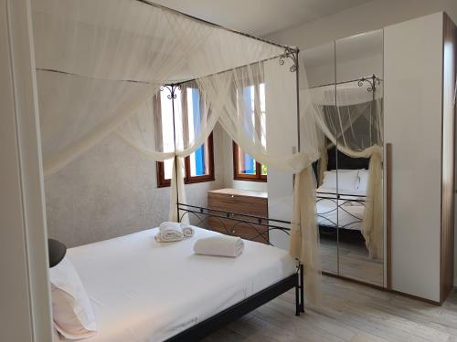 a bedroom with a bed with white sheets and a mirror at Luxury Apartments Riva Vena in Chioggia