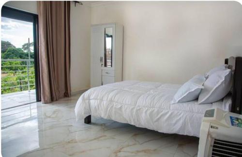 a bedroom with a white bed and a large window at Exotic Mimosa Serviced Apartment Accommodation in Lusaka